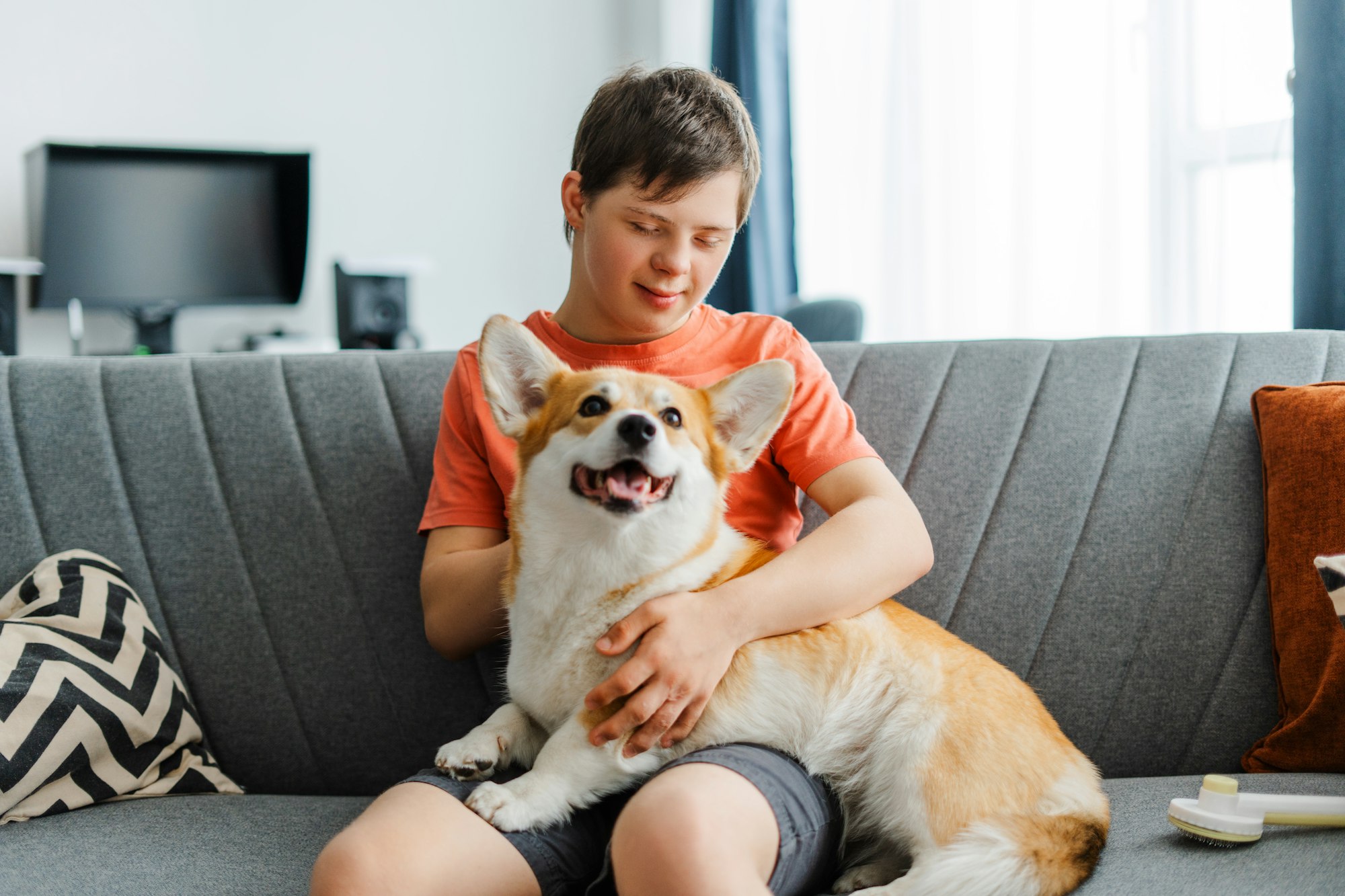 Smiling caucasian boy embracing his pet and sitting on the sofa at home